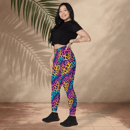 Woman wearing colorful leopard print leggings and a black crop top against a beige wall.