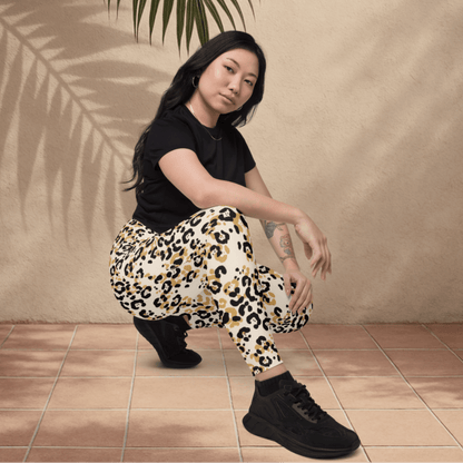 Woman wearing leopard print pants and black shoes sitting on a tiled floor.
