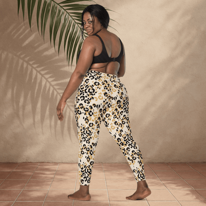 Woman wearing leopard print pants and a black sports bra against a beige wall.