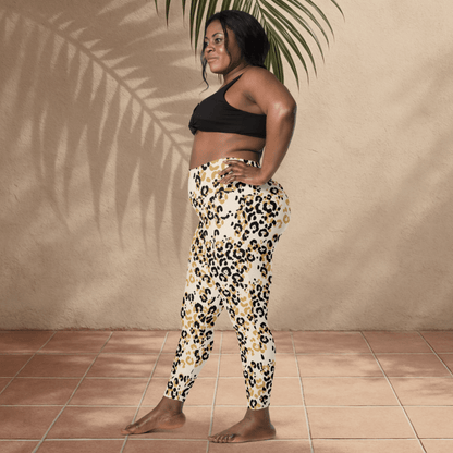 Woman wearing a black sports bra and leopard print leggings standing against a beige wall.